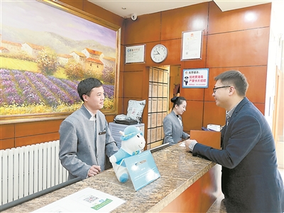 北京市西城區(qū)某快捷酒店的前臺接待曹健濤（左一）表示，他所在的快捷酒店成為越來越多來京出差干部的入住選擇，明顯感覺許多干部的節(jié)約意識增強了，會盤算著幫公家省錢了。