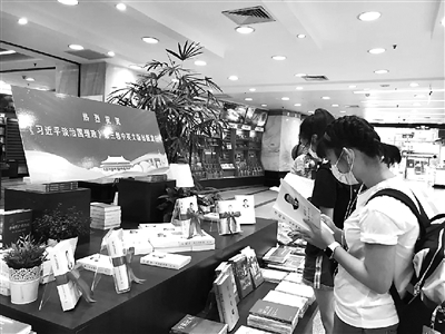圖為讀者近日在上海書城設(shè)置的《習(xí)近平談治國理政》第三卷專架展臺前閱讀。 外文出版社供圖
