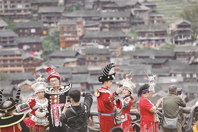 近年來(lái)，貴州省雷山縣不斷推動(dòng)高鐵資源和旅游景區(qū)深度融合，方便各地游客前來(lái)體驗(yàn)苗族風(fēng)情，觀賞苗寨美景，為古老苗寨的鄉(xiāng)村振興注入活力。圖為今年國(guó)慶假期，游客穿著民族服裝在該縣西江千戶苗寨觀景臺(tái)拍照留念。新華社發(fā)（林世康 攝）