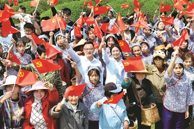 江西省德興市香屯街道辦江村千畝茶園，兩名基層扶貧干部揮舞著黨旗，和大家一起唱起了《唱支山歌給黨聽》。  （圖片來源：視覺中國）