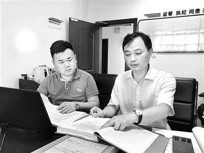 圖為肖鷹(右)正在查閱相關(guān)案件資料。