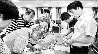 圖為張小華(右一)生前在三角塘鎮(zhèn)給部分困難群眾清退水廠違規(guī)收取的費(fèi)用。(資料圖片)